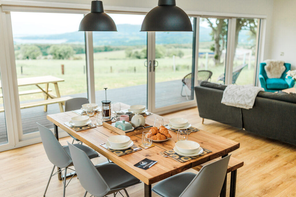 Open-plan living space with a breakfast table set and panoramic views across the Solway Firth.