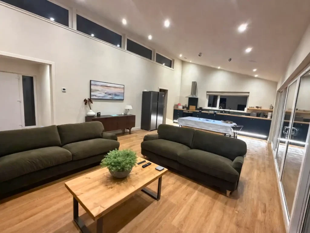 Spacious open-plan living and kitchen area with green sofas and modern interior at Gatehouse Luxury Lodges.